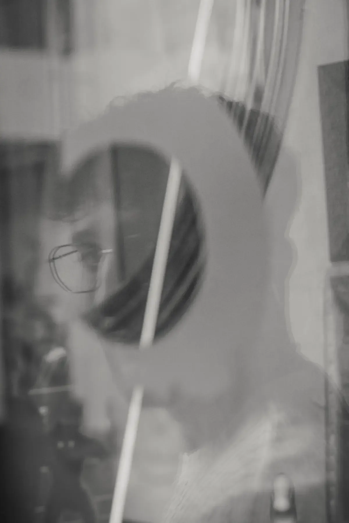 Azan Blues, retrato en blanco y negro tras el reflejo de una guitarra